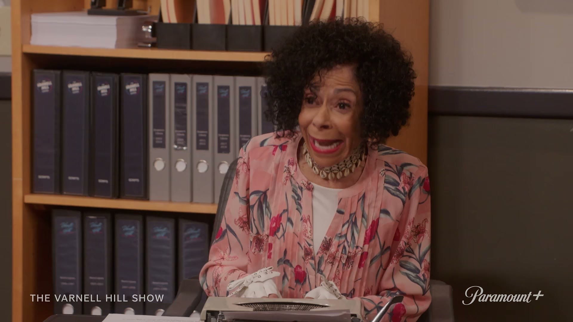 from The Varnell Hill Show on Paramount+ trailer — floral blouse doing the heavy lifting at the desk