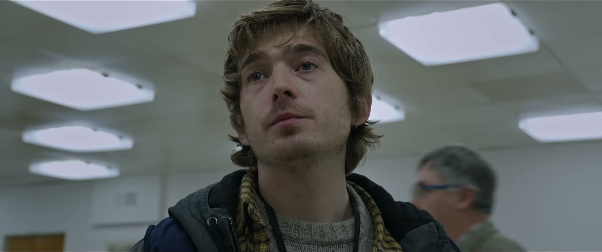Austin Abrams in Resident Evil — the plaid scarf is honestly doing all the work here